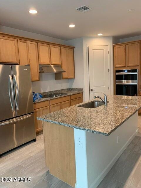 kitchen with stainless steel appliances, light hardwood / wood-style floors, a center island with sink, and sink