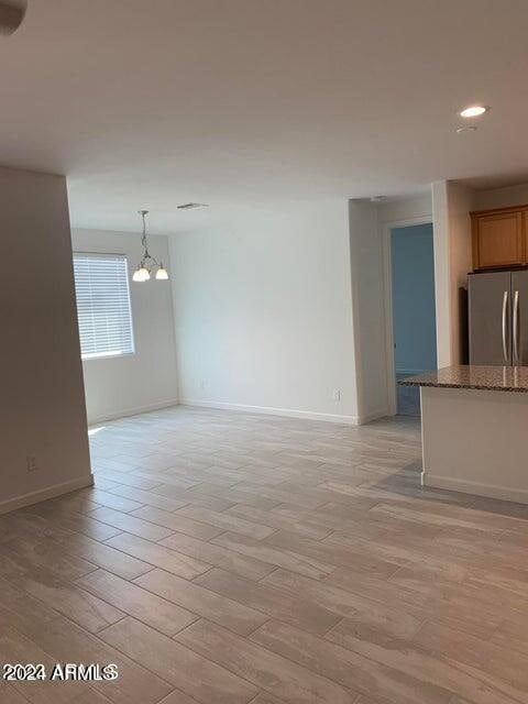 unfurnished living room featuring an inviting chandelier and light hardwood / wood-style floors