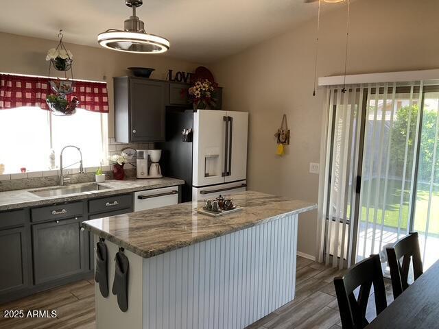 kitchen featuring white appliances, a sink, healthy amount of natural light, and light wood-style flooring