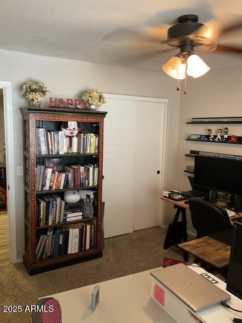 carpeted home office featuring ceiling fan