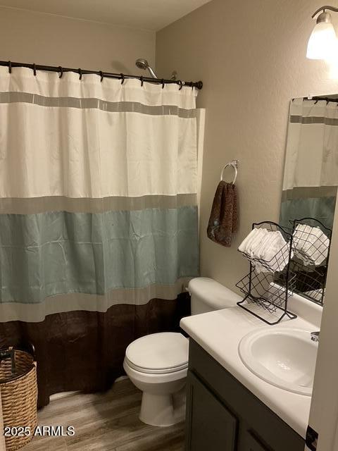 bathroom featuring wood finished floors, vanity, toilet, and curtained shower
