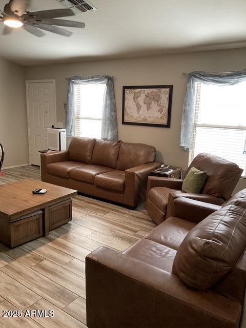living room with light wood-style floors, ceiling fan, and plenty of natural light