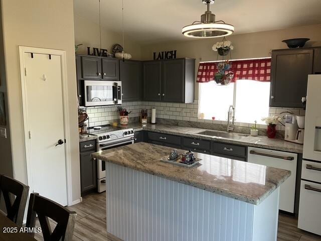 kitchen featuring electric range oven, stainless steel microwave, a sink, dishwasher, and white refrigerator with ice dispenser