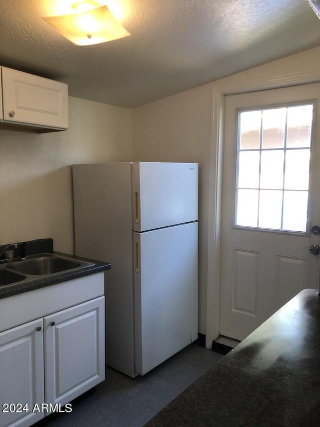 kitchen with a textured ceiling, sink, white refrigerator, and white cabinets