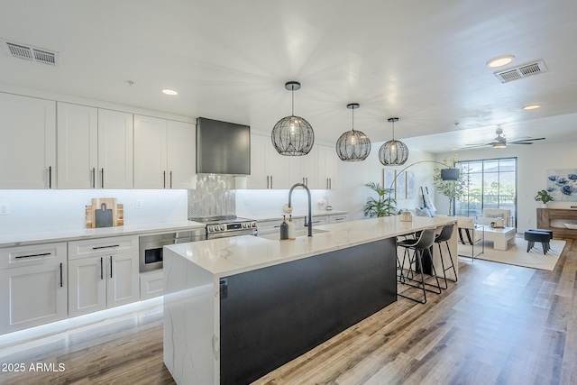 kitchen featuring backsplash, stainless steel electric range, visible vents, and light wood-style floors