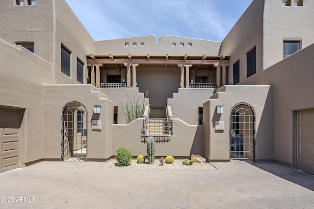 pueblo-style house with a gate and stucco siding