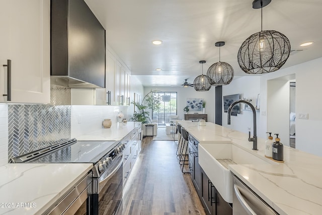kitchen featuring light stone counters, recessed lighting, wood finished floors, stainless steel electric stove, and pendant lighting