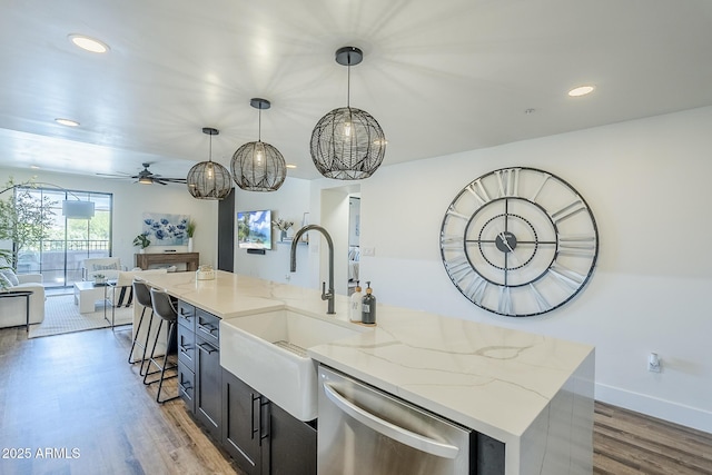 kitchen featuring stainless steel dishwasher, wood finished floors, open floor plan, recessed lighting, and a sink