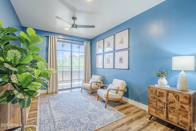 living area featuring baseboards, ceiling fan, and wood finished floors