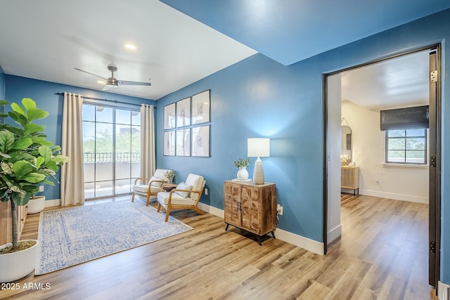 living area with wood finished floors, baseboards, ceiling fan, radiator heating unit, and arched walkways