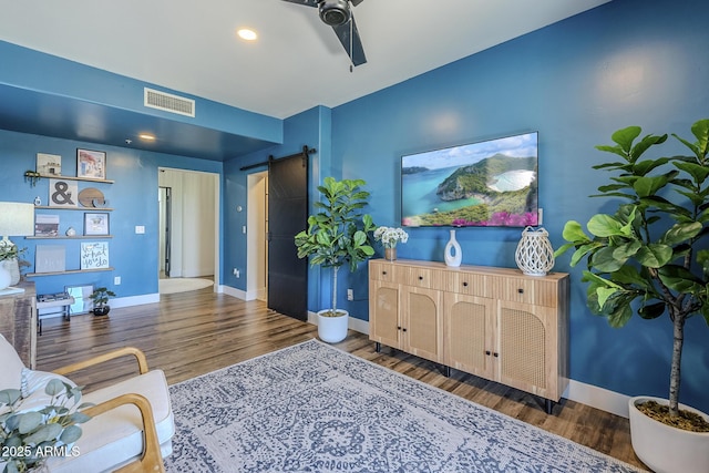 living room featuring a barn door, recessed lighting, baseboards, wood finished floors, and visible vents