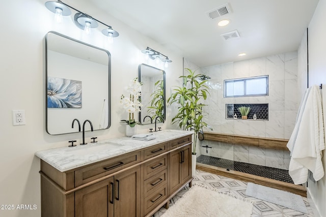 full bath featuring a sink, tiled shower, and visible vents
