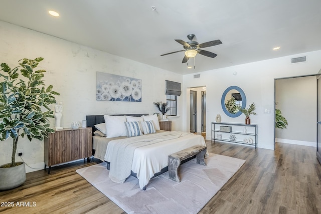 bedroom featuring a ceiling fan, visible vents, and wood finished floors
