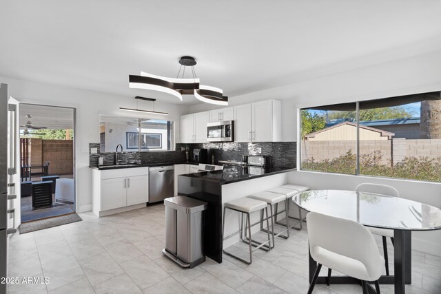 3758 E Sunnyside Dr, Phoenix, AZ 85028 - kitchen with a sink, decorative backsplash, stainless steel appliances, a peninsula, and white cabinetry