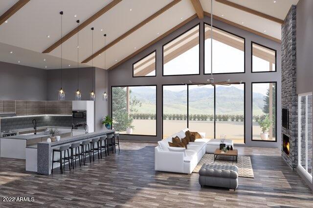 living room featuring beamed ceiling, a fireplace, plenty of natural light, and high vaulted ceiling