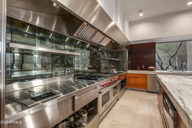 kitchen with light tile patterned flooring, range hood, backsplash, double oven range, and light stone countertops