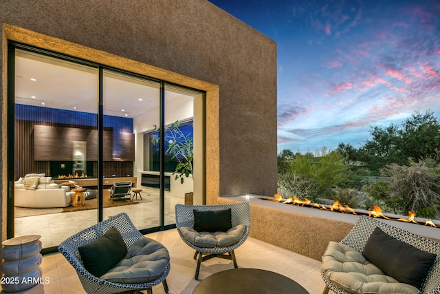 patio terrace at dusk featuring an outdoor living space with a fire pit