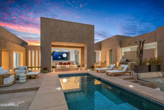 pool at dusk featuring an outdoor living space, a patio, and a grill