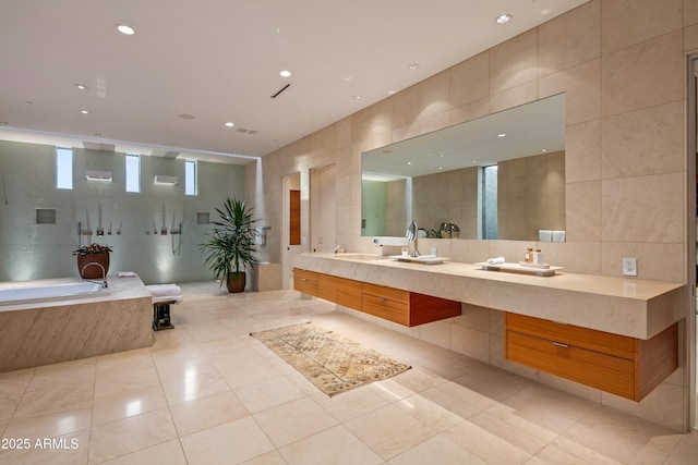 bathroom featuring a relaxing tiled tub, tile patterned floors, vanity, and tile walls