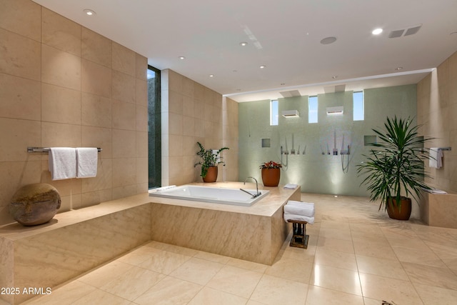 bathroom featuring tile walls, tile patterned flooring, and tiled bath