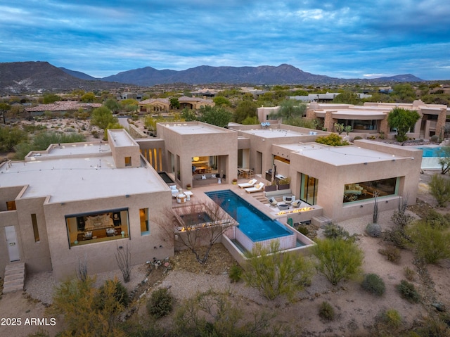 back of property with a mountain view and a patio area