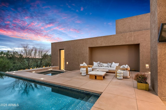 pool at dusk featuring an in ground hot tub, an outdoor living space, and a patio area