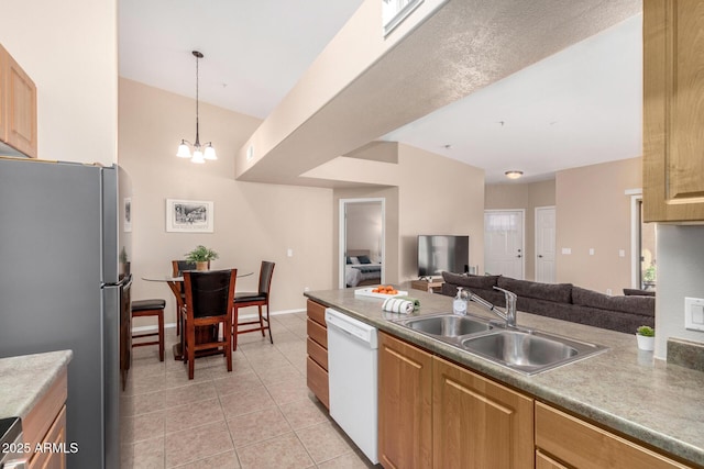 kitchen featuring dishwasher, sink, stainless steel fridge, hanging light fixtures, and light tile patterned floors