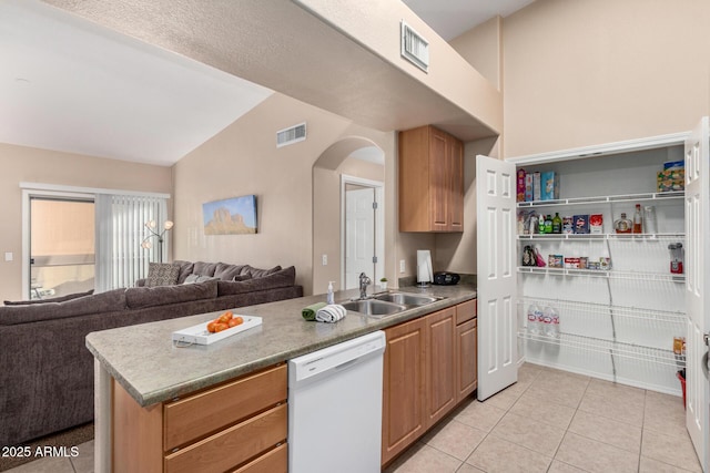 kitchen featuring white dishwasher, sink, light tile patterned floors, and lofted ceiling