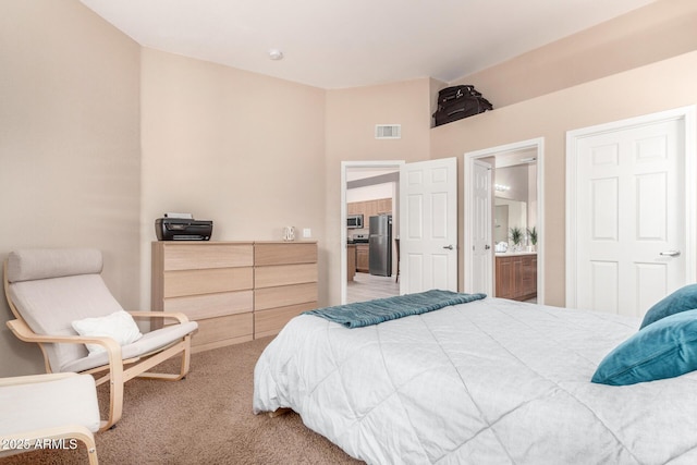 carpeted bedroom with connected bathroom and stainless steel refrigerator