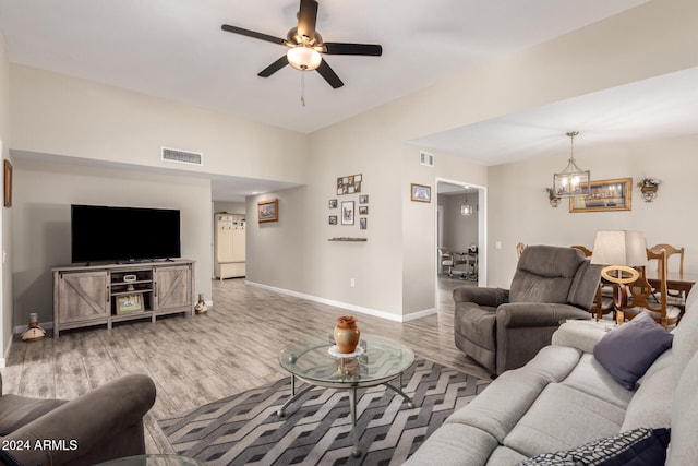 living room with ceiling fan with notable chandelier and wood-type flooring