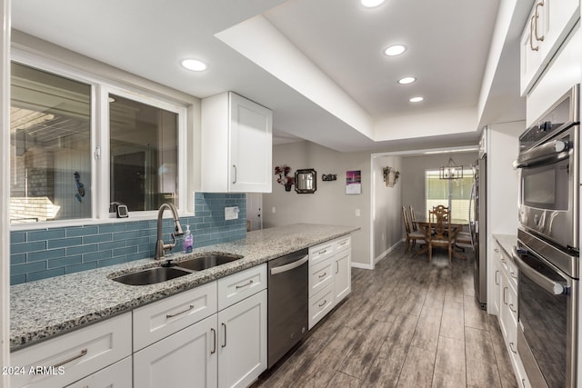 kitchen featuring light stone countertops, white cabinetry, sink, dark wood-type flooring, and appliances with stainless steel finishes