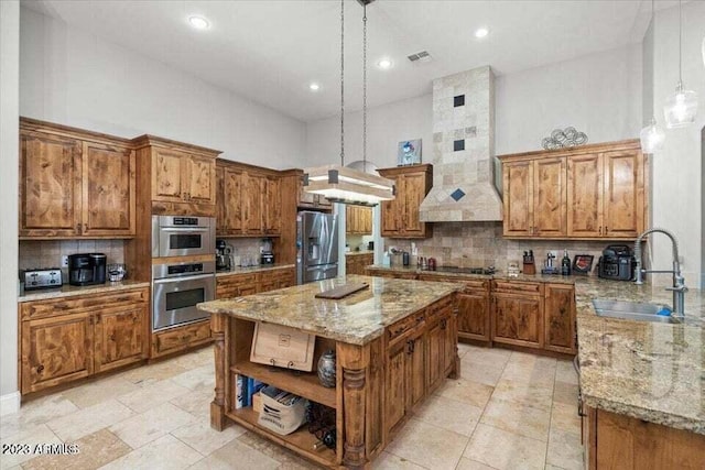 kitchen featuring appliances with stainless steel finishes, light stone counters, a center island, backsplash, and sink