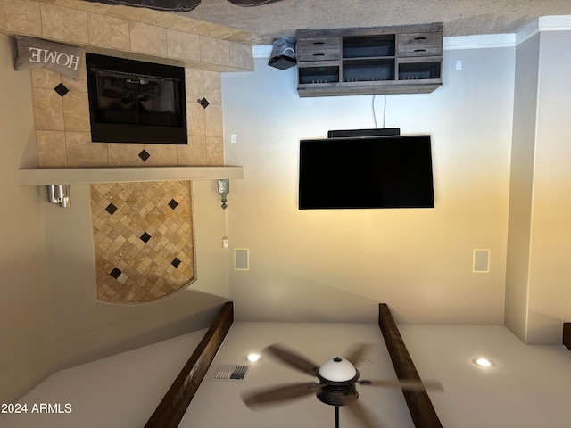 interior space featuring ceiling fan, a tile fireplace, and a textured ceiling