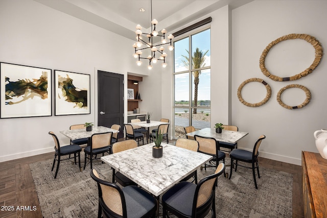 dining space featuring a water view, dark wood-type flooring, and a chandelier