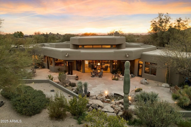 back house at dusk with a patio area