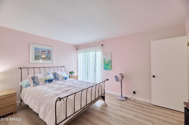 bedroom featuring light wood finished floors and baseboards