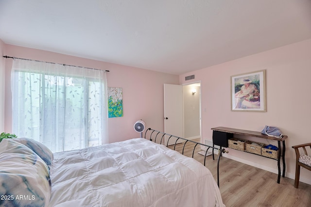 bedroom with baseboards, visible vents, and wood finished floors