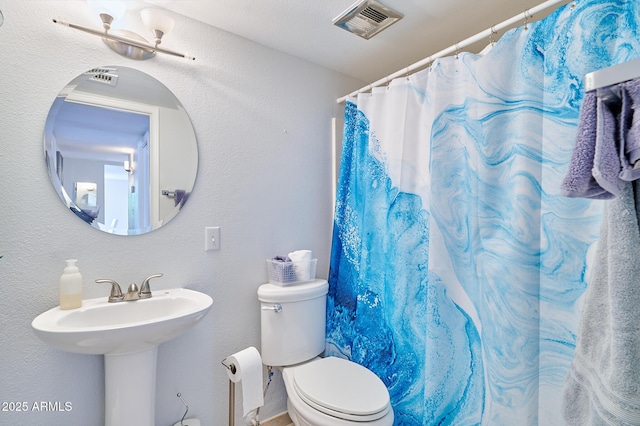 bathroom featuring a sink, curtained shower, toilet, and visible vents
