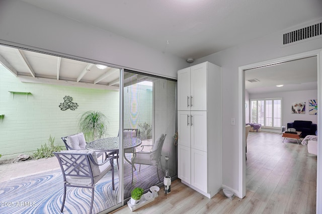 dining area with brick wall, baseboards, light wood-type flooring, and visible vents