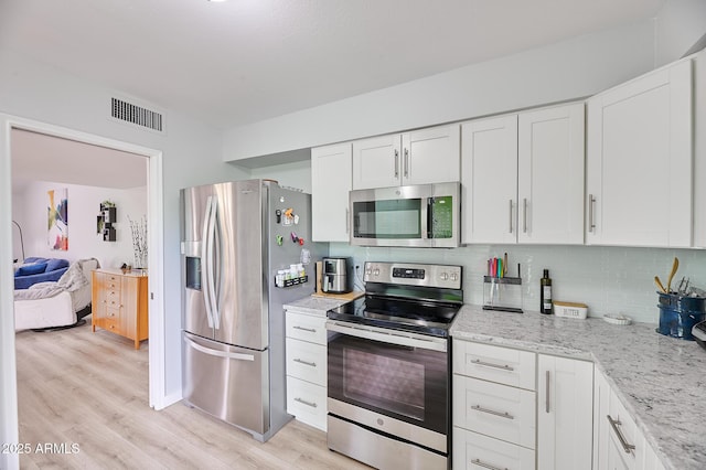 kitchen featuring white cabinets, light wood-type flooring, visible vents, backsplash, and appliances with stainless steel finishes