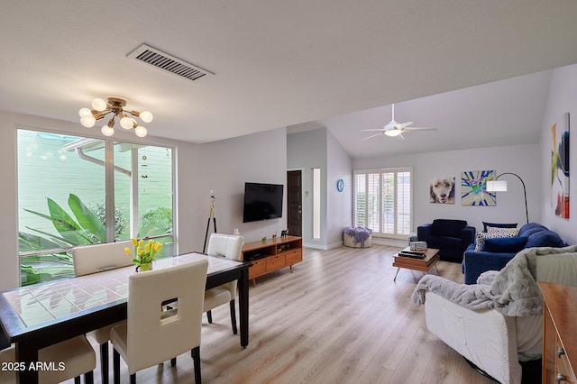 living area with light wood finished floors, ceiling fan with notable chandelier, visible vents, baseboards, and lofted ceiling