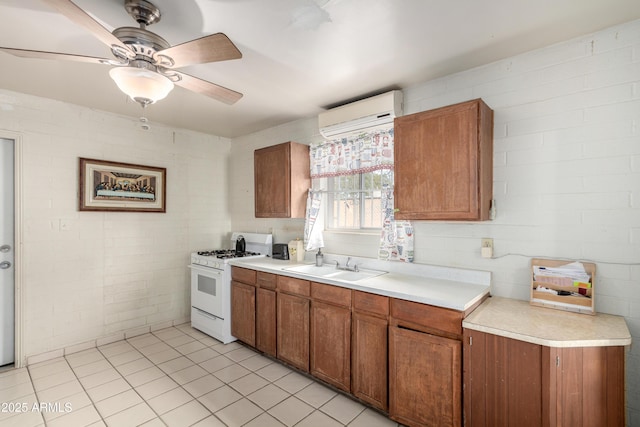 kitchen featuring sink, gas range gas stove, a wall mounted air conditioner, light tile patterned floors, and ceiling fan