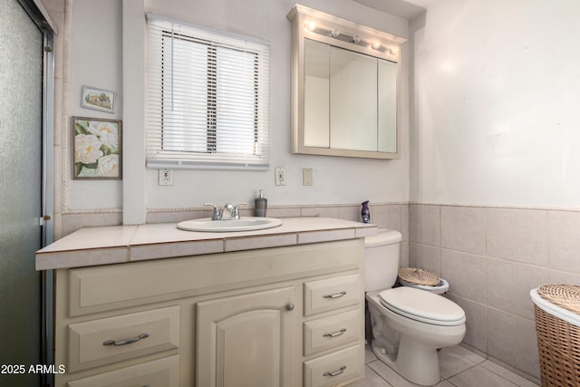 bathroom featuring tile walls, vanity, tile patterned floors, and toilet