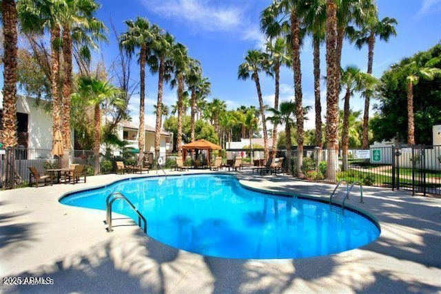 pool with a patio area and fence