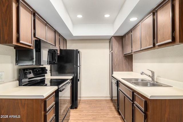 kitchen featuring black appliances, a sink, light countertops, and light wood-style floors