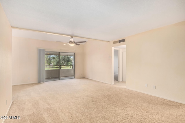 empty room with a ceiling fan, visible vents, light carpet, and baseboards