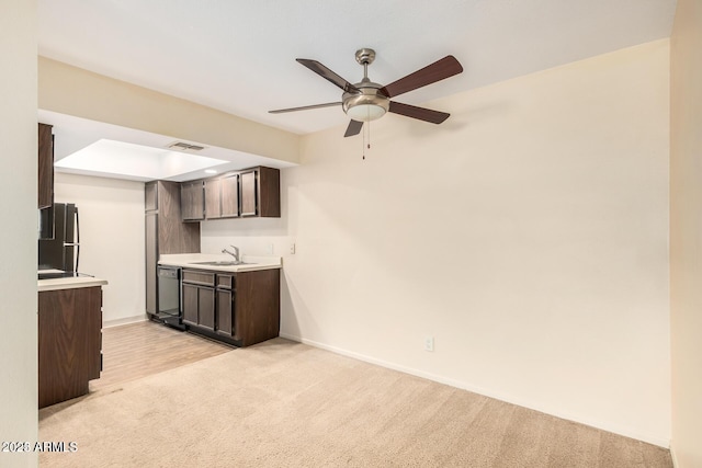 kitchen featuring dishwasher, light colored carpet, freestanding refrigerator, light countertops, and a sink