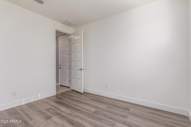 unfurnished room with baseboards, visible vents, and wood finished floors