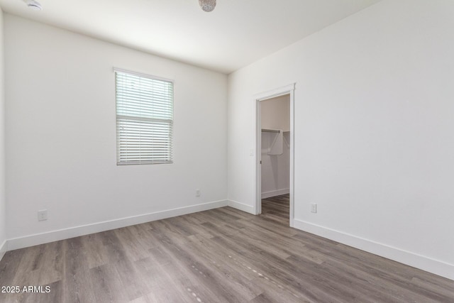 spare room with baseboards and wood finished floors