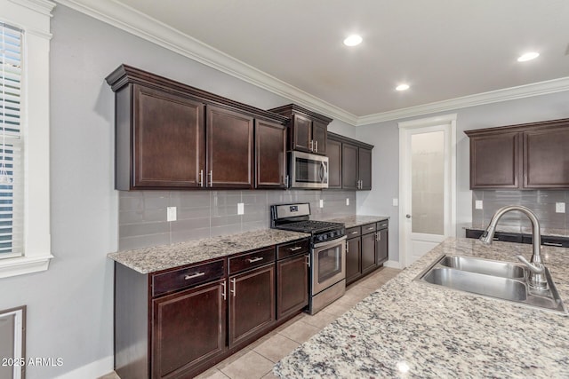 kitchen with crown molding, dark brown cabinetry, appliances with stainless steel finishes, a sink, and tasteful backsplash